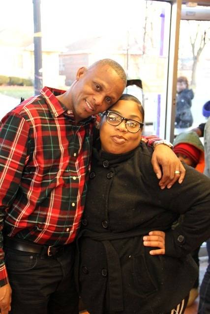 Two people happily pose for a photo inside.