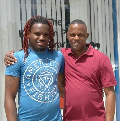 Two men smiling, posing, standing at the library entrance.
