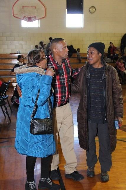 Three people talking in a gymnasium.