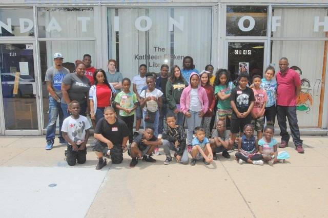 Group of kids posing in front of a library.