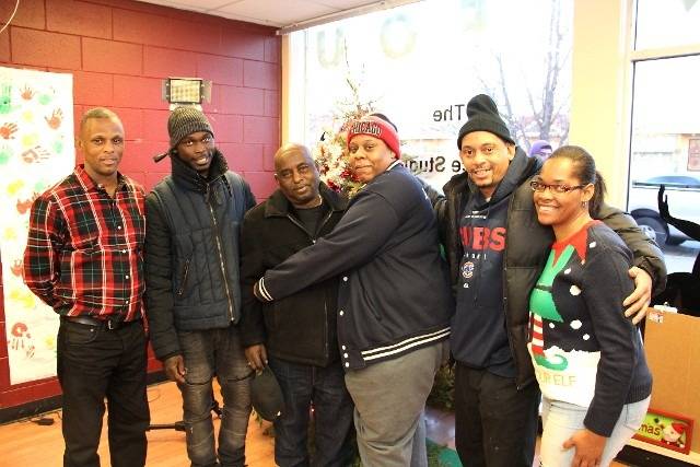 A group of diverse people smiling and posing for a photo, possibly at a holiday gathering or event.