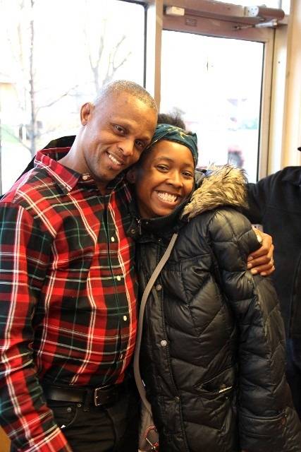 Two smiling people, a man in a plaid shirt and a woman in a black jacket, pose for a photo.