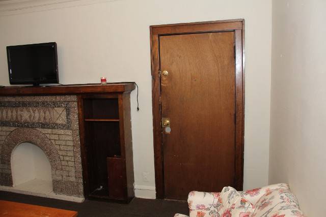 Living room with fireplace, TV, and wooden door.