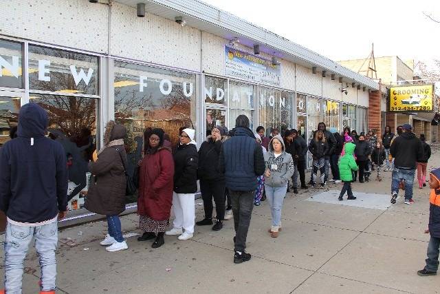 People wait in line outside a building.