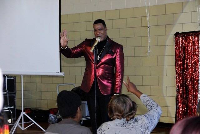 Singer performing in red suit, audience.