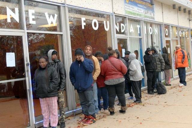 People queuing outside a building, "New Foundation of Hope" sign.