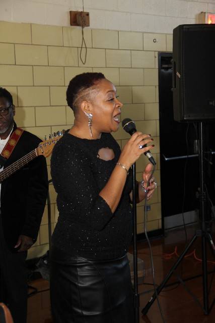 Woman singing with microphone and band.