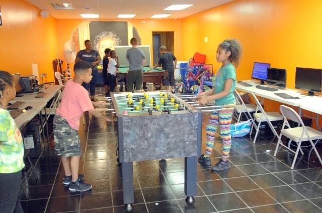 Kids playing foosball in brightly colored room.