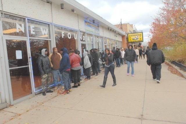 People wait in line outside a building labeled "New Foundation Hope".