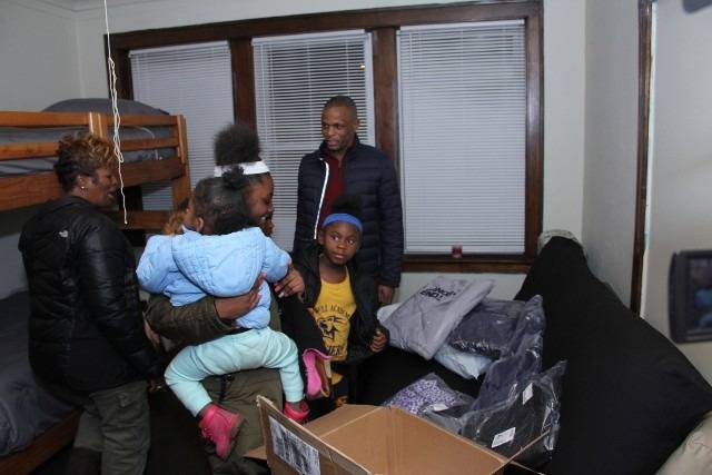 Family in a room with bunk beds and donations.