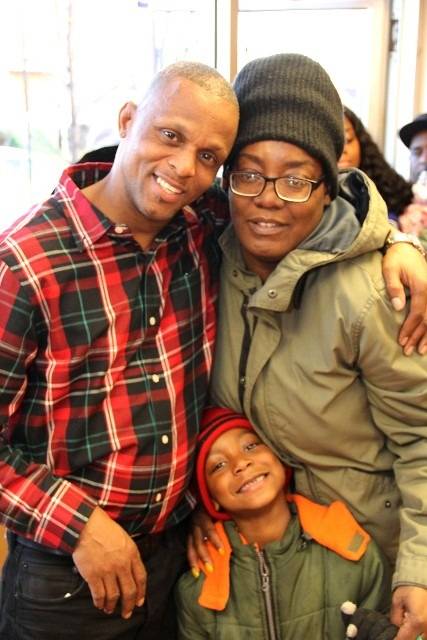 Three smiling people embracing.