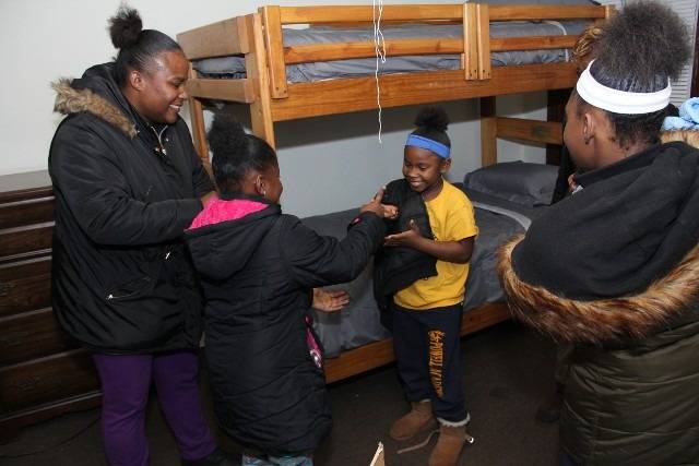 Family helping child with coat in new bedroom