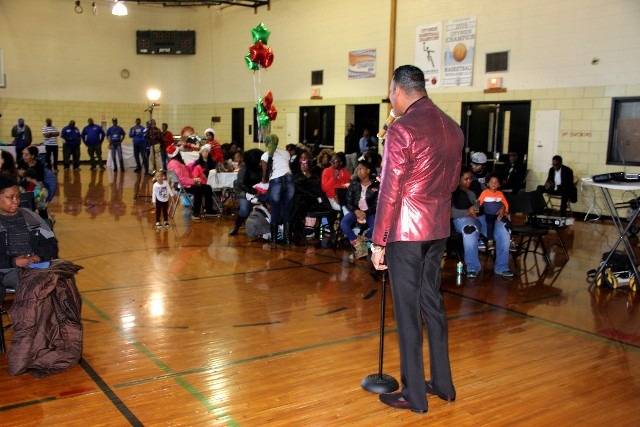 Man in shiny red jacket speaking at event.