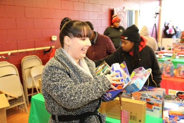 Woman holding toy in front of a table.