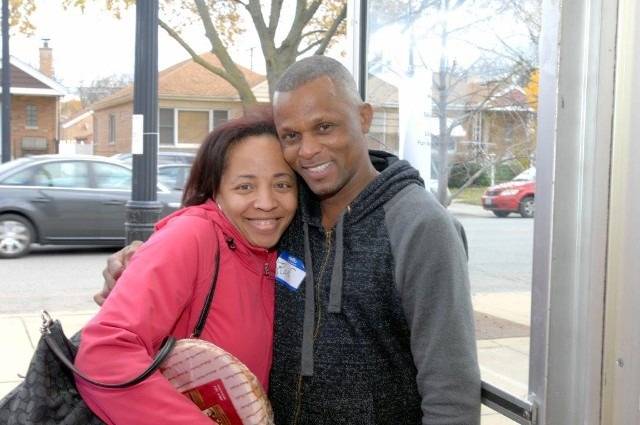 Two smiling people hugging outside.